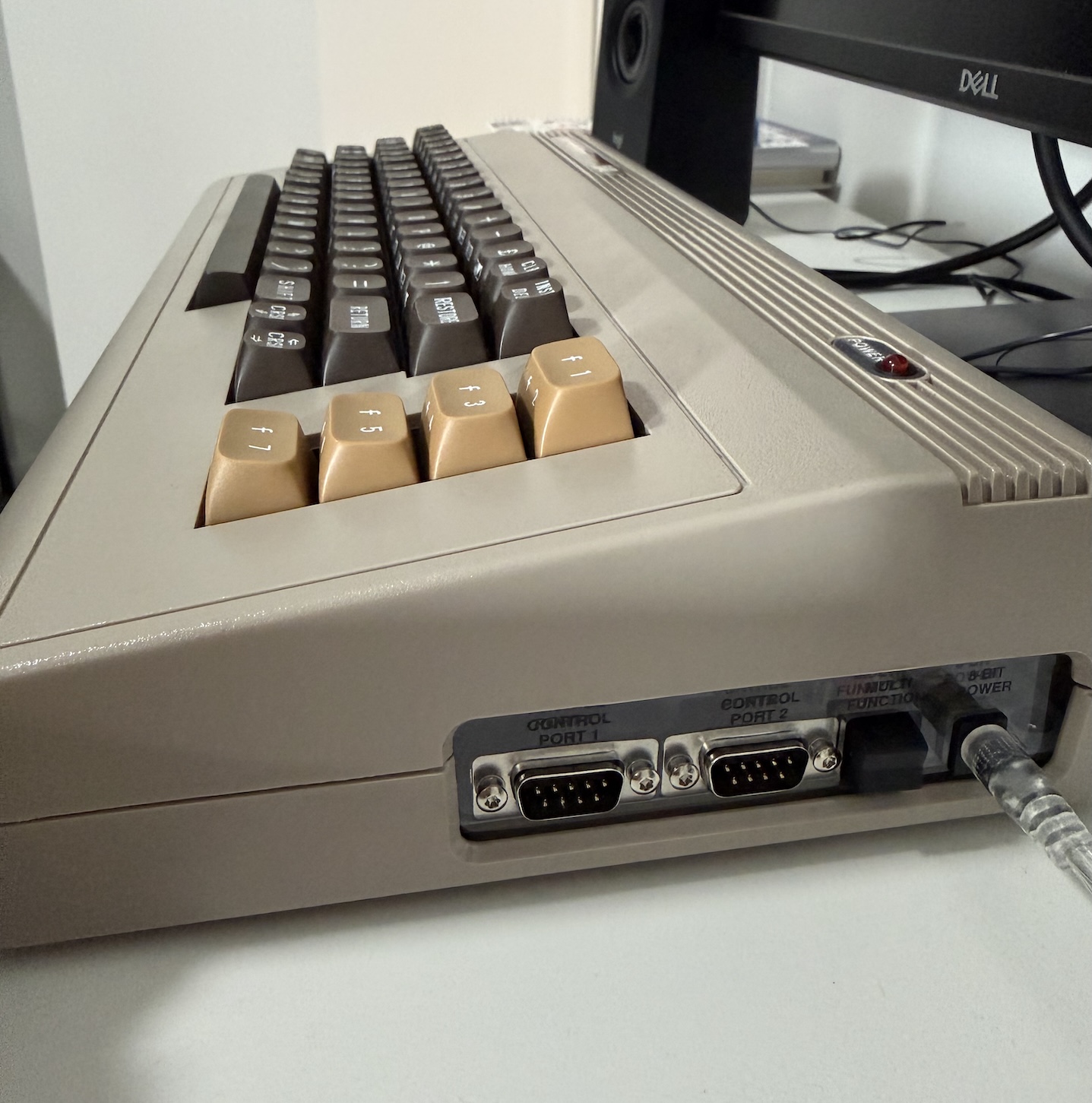 Side view of the Commodore 64 Ultimate showing power switch, power cord, and joystick ports. You can see the function keys and remainder of the keyboard sliding away from view.